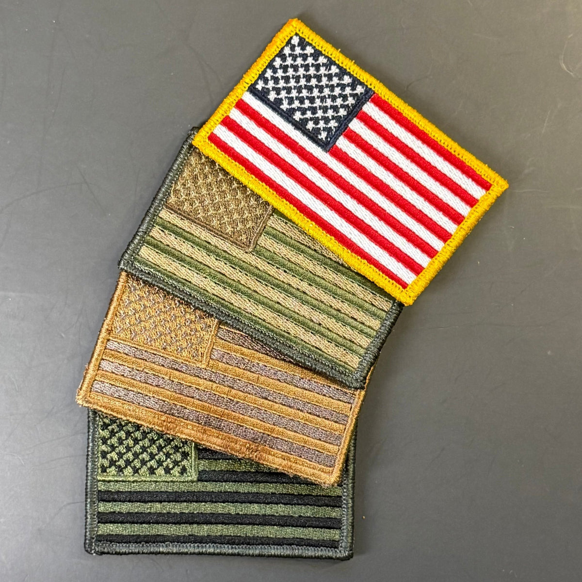 Red, white and blue American flag patch with yellow border above an olive-green flag patch and its hook backing