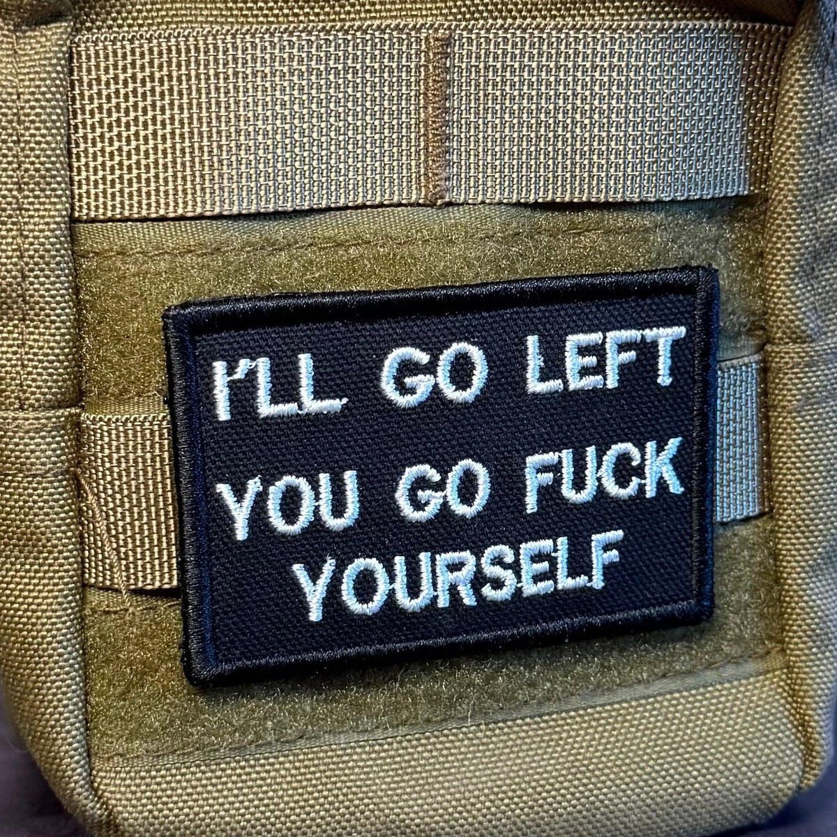 Go F*ck Yourself patch in black with white lettering, mounted on an olive backpack