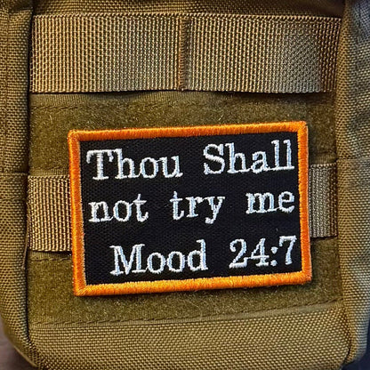 Thou Shall Not Try Me, Mood 24:7 patch in black with white lettering and an orange border, mounted on an olive backpack