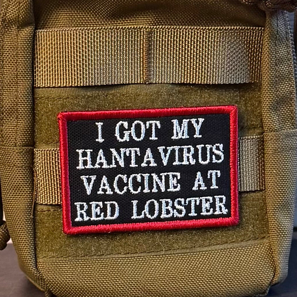 I Got My Hantavirus Vaccine At Red Lobster patch in black with white lettering and a red border, mounted on an olive backpack