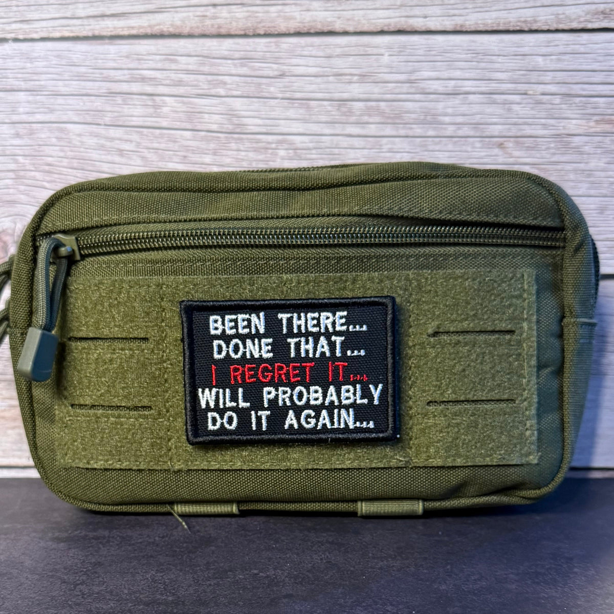 Been There, Done That, I Regret It, Will Probably Do It Again patch in black with white and red lettering, mounted on an olive utility pouch