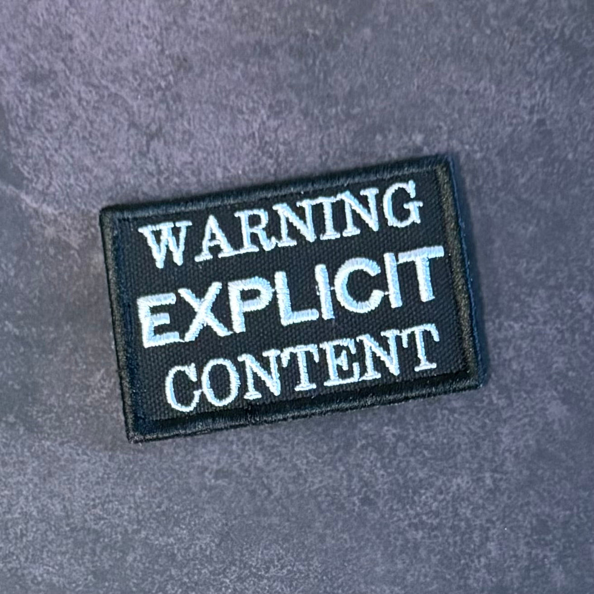 Front view of Explicit Content Warning patch in black with white lettering