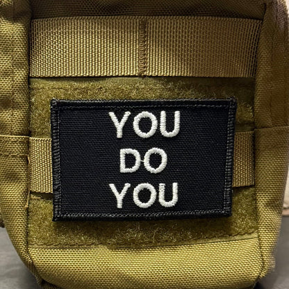 You Do You patch in black with white lettering, mounted on an olive backpack
