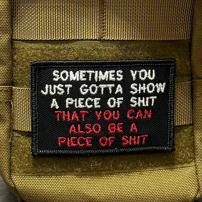 Sometimes You Just Gotta Show a Piece of Shit patch in black with white and red lettering, mounted on an olive backpack