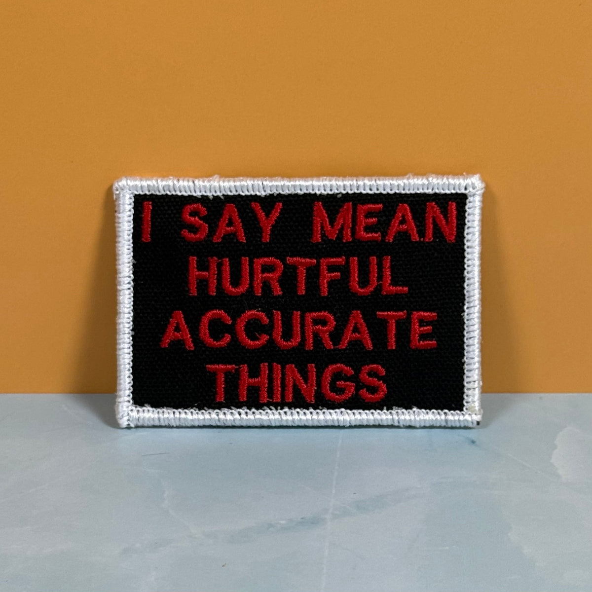 Front view of I Say Mean, Hurtful, Accurate Things patch in black with red lettering and white border