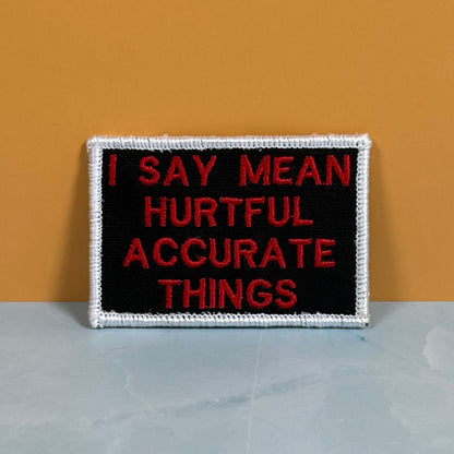 Front view of I Say Mean, Hurtful, Accurate Things patch in black with red lettering and white border