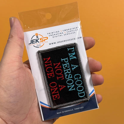 I'm A Good Person, Not A Nice One patch in black with pale blue and red lettering, retail package held in hand