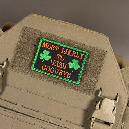 Most Likely To Irish Goodbye patch in black with gold lettering, green shamrocks and a green border, mounted on a tan plate carrier
