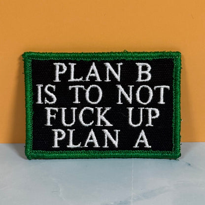 Front view of Plan B, Don't Fuck Up Plan A patch in black with white lettering and a green border