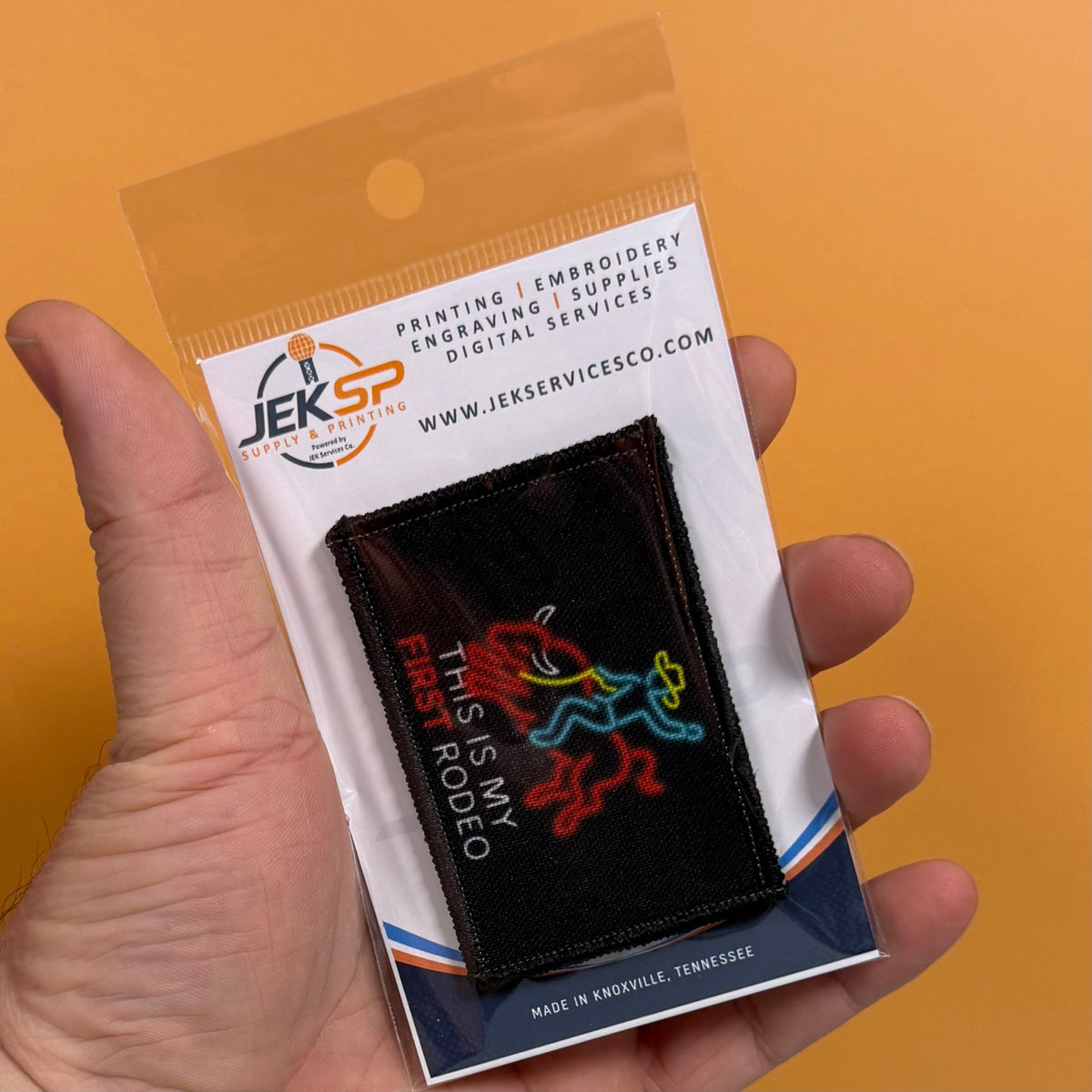 My First Rodeo patch in black with a red, yellow and blue rodeo rider and white lettering, retail package held in a hand