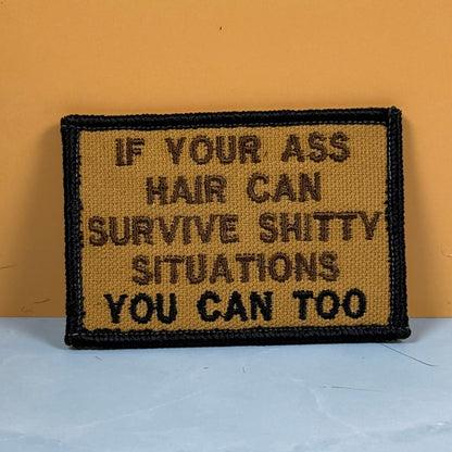 Front view of If Your Ass Hair Can Survive patch in tan with dark lettering