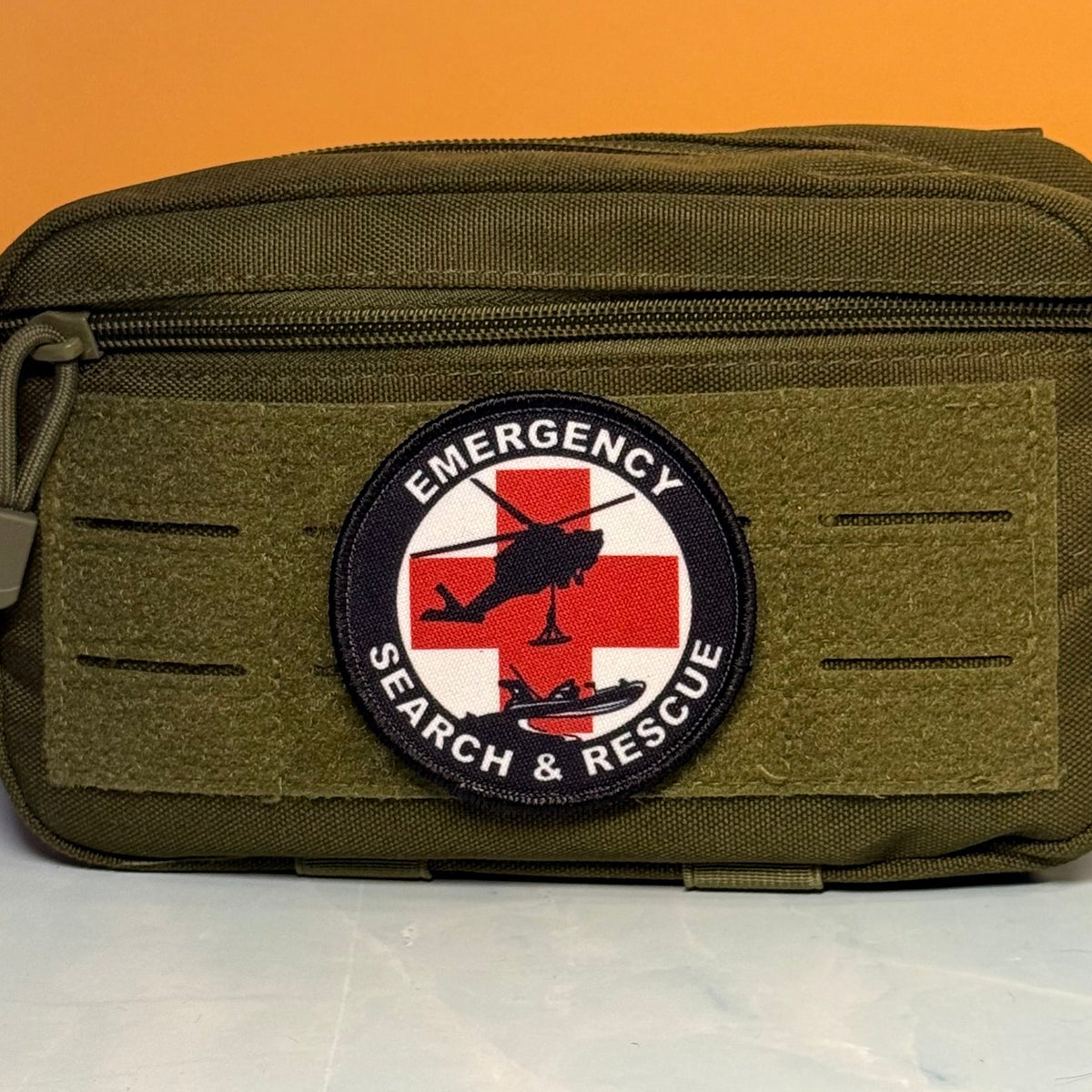 Round Emergency Search and Rescue printed patch with a red cross and black aircraft silhouettes, mounted on an olive utility pouch