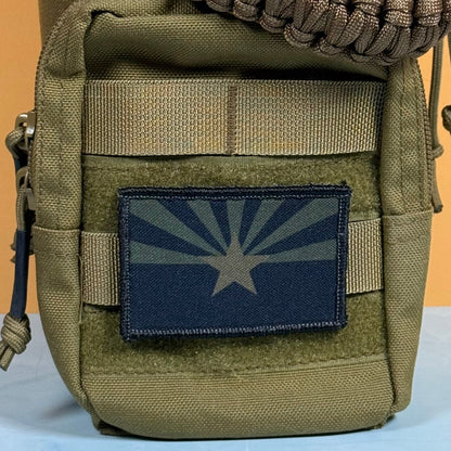 Arizona State Flag patch in subdued tan and dark blue Arizona flag with a star and radiating rays, mounted on an olive backpack