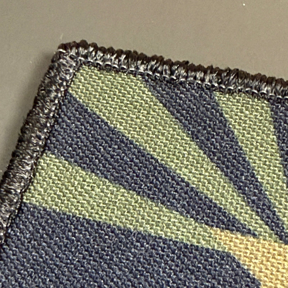 Arizona State Flag patch in subdued tan and dark blue Arizona flag with a star and radiating rays, close-up of embroidery
