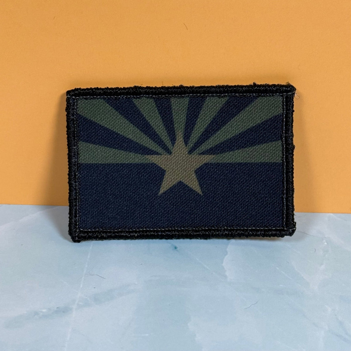 Front view of Arizona State Flag patch in subdued tan and dark blue Arizona flag with a star and radiating rays