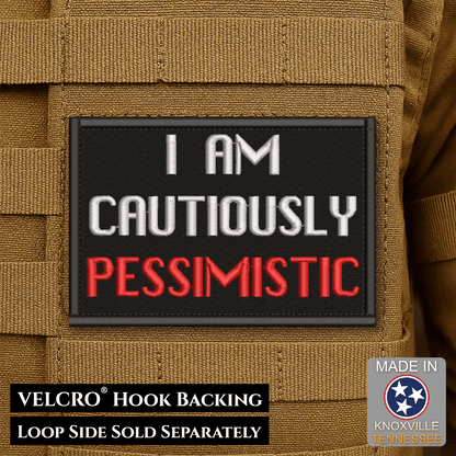 Front design and hook backing of Cautiously Pessimistic patch in black with white and red lettering