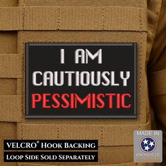 Front design and hook backing of Cautiously Pessimistic patch in black with white and red lettering