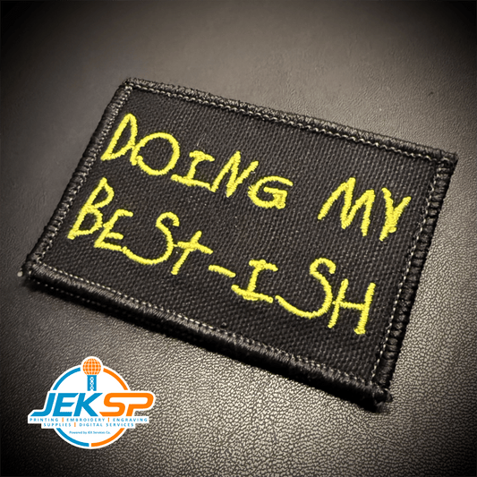 Front view of Doing My Best-ish patch in black with yellow handwritten lettering