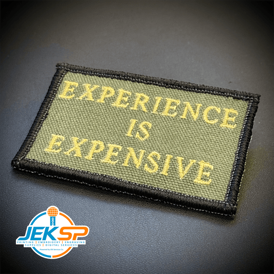 Front view of Experience Is Expensive patch in olive green with yellow lettering