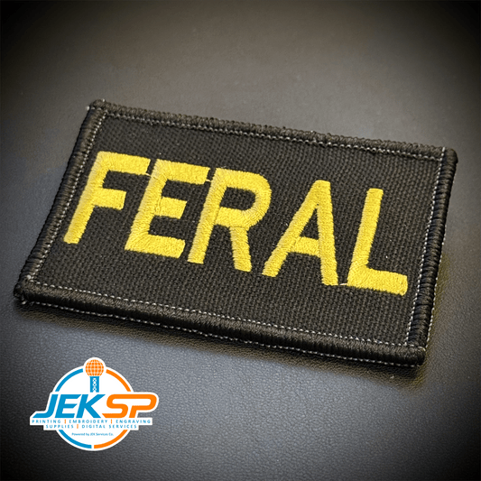 Front view of Feral & Wild patch in black with yellow FERAL lettering