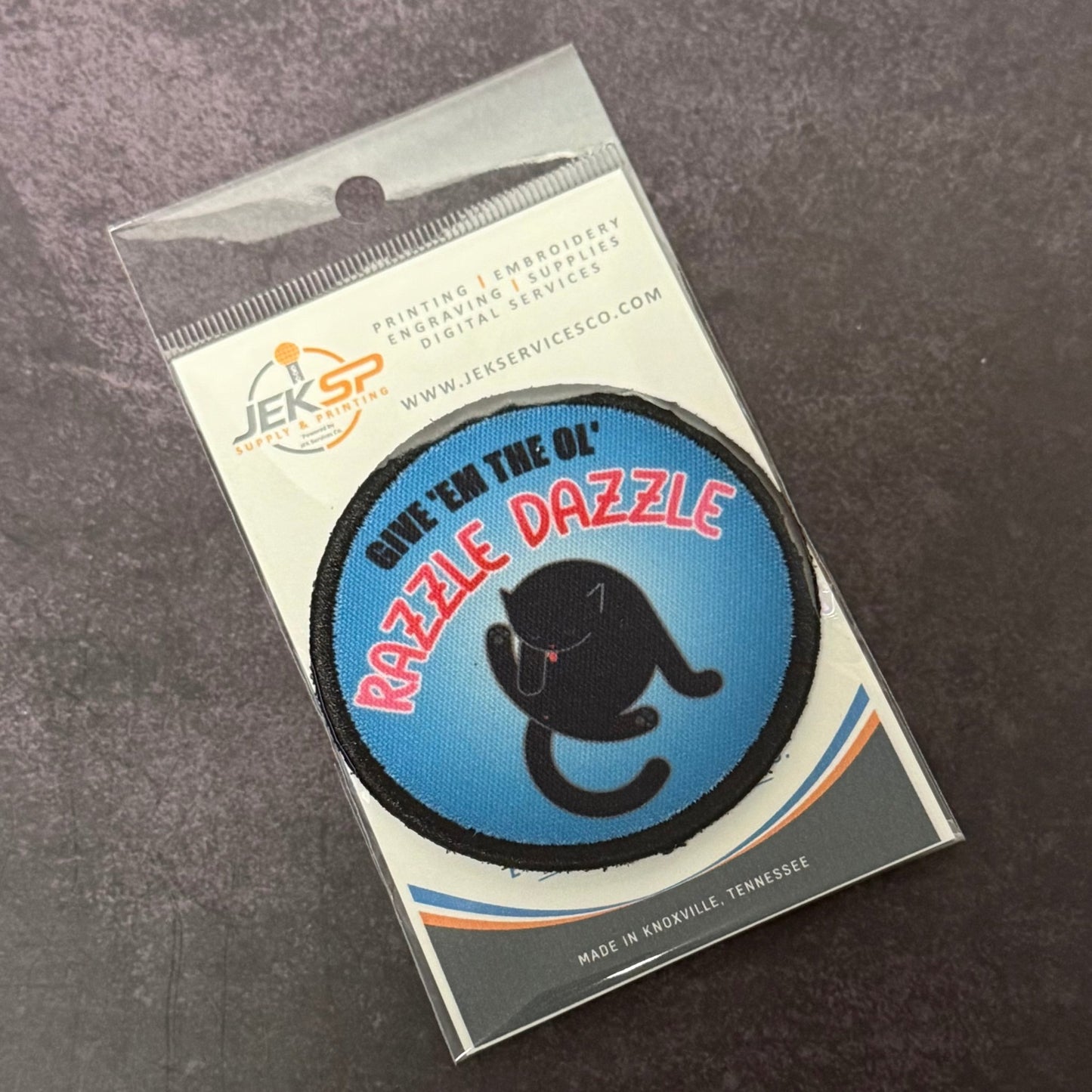 Give 'Em The Razzle Dazzle Funny Morale Patch, 3" Round | Made in USA | VELCRO® Brand Hook Backing - LoneStar Adhesive