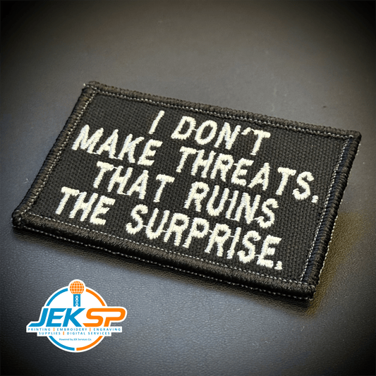 Front view of I Don't Make Threats, That Ruins The Surprise patch in black with white lettering