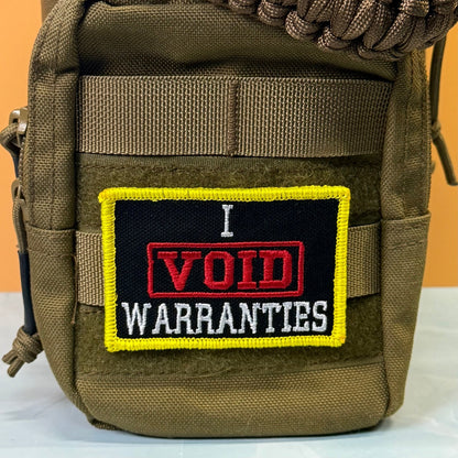 I Void Warranties patch in black with a red VOID stamp, white lettering and yellow border, mounted on an olive backpack