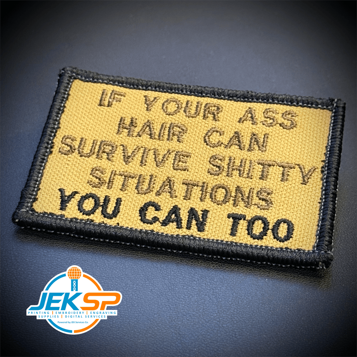 Front view of If Your Ass Hair Can Survive patch in tan with dark lettering