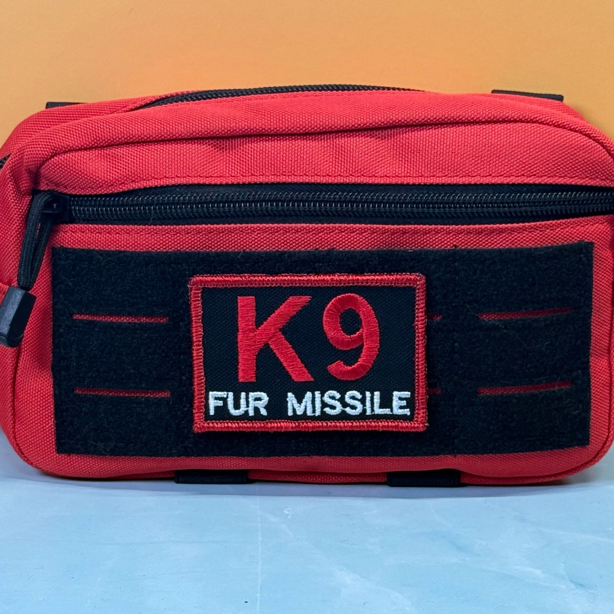 K-9 Fur Missile patch in black with red K9 and border and white FUR MISSILE lettering, mounted on a red utility pouch