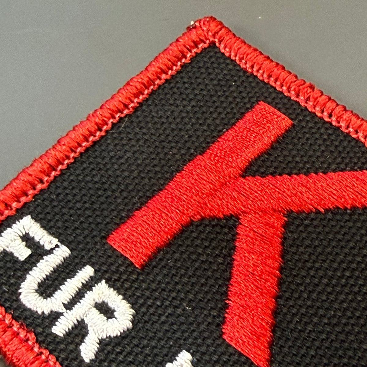 K-9 Fur Missile patch in black with red K9 and border and white FUR MISSILE lettering, close-up of embroidery