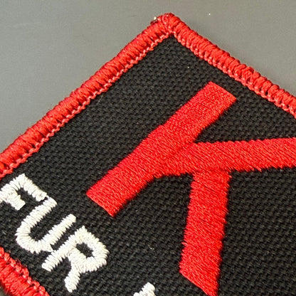 K-9 Fur Missile patch in black with red K9 and border and white FUR MISSILE lettering, close-up of embroidery