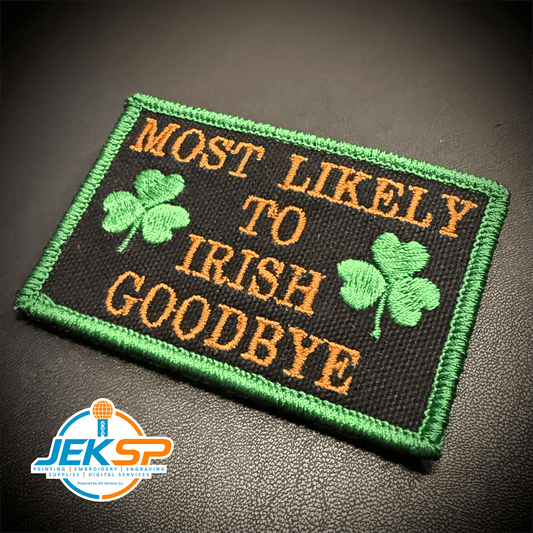 Front view of Most Likely To Irish Goodbye patch in black with gold lettering, green shamrocks and a green border