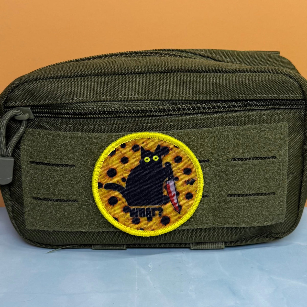 Murder Cat & Sunflowers patch in yellow with a black cat, sunflowers and a red knife, mounted on an olive utility pouch