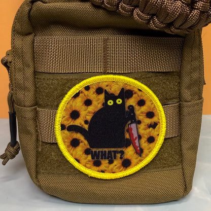 Murder Cat & Sunflowers patch in yellow with a black cat, sunflowers and a red knife, mounted on an olive backpack