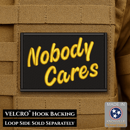 Front design and hook backing of Nobody Cares patch in black with yellow script lettering