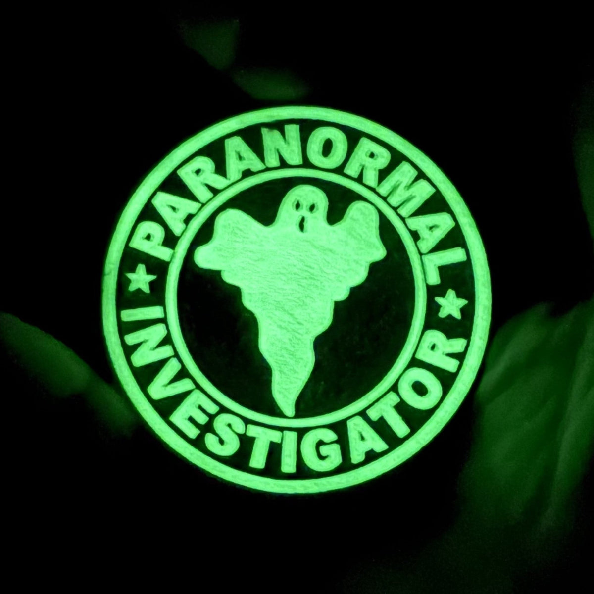 Paranormal Investigator patch glowing green in the dark, with a ghost silhouette and circular lettering