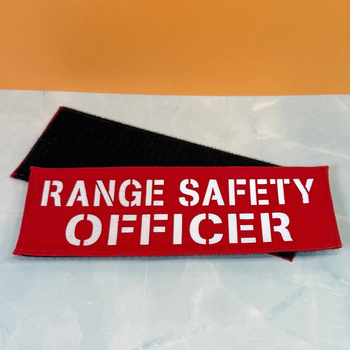 Range Safety Officer Patches & ID Panels patch in red with white Range Safety Officer lettering, front beside hook backing