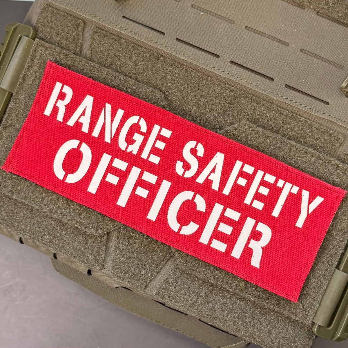 Range Safety Officer Patches & ID Panels patch in red with white Range Safety Officer lettering, mounted on a tan plate carrier