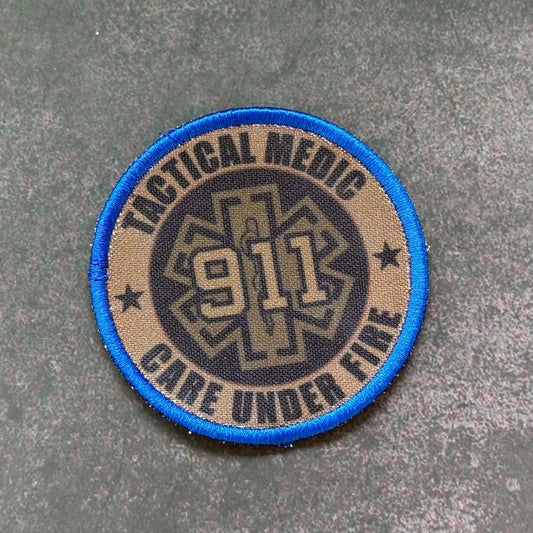 Front view of Tactical EMT Paramedic patch in tan and black with a blue border, star-of-life symbol and 911 numerals