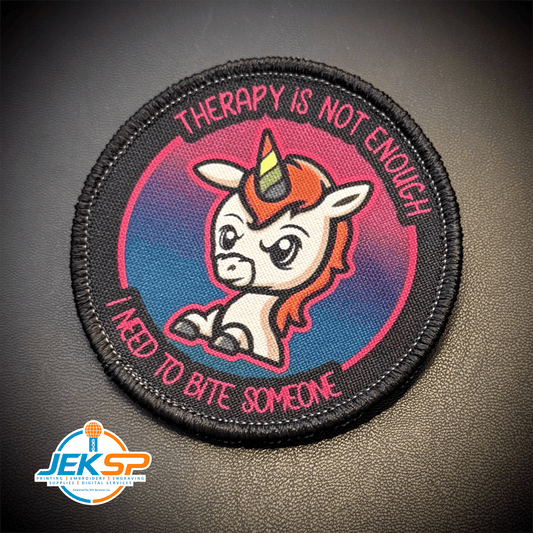 Front view of Therapy Unicorn patch in black and purple with pink lettering and a white unicorn