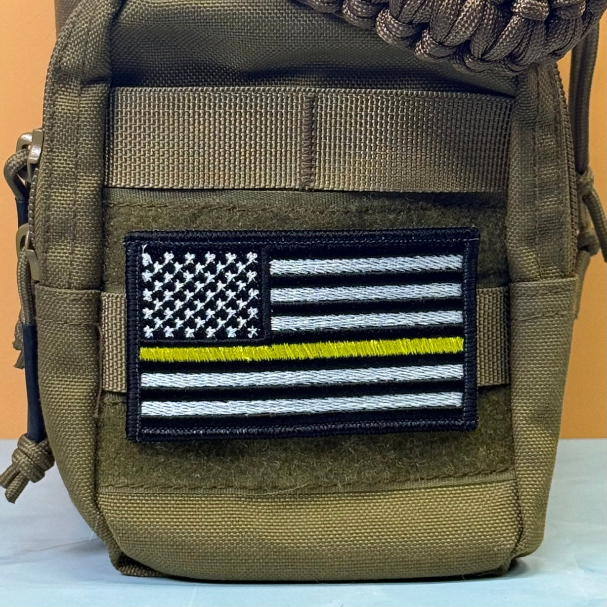 Thin Yellow Line American Flag patch in black and white American flag with one yellow stripe, mounted on an olive backpack
