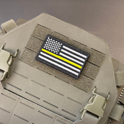 Thin Yellow Line American Flag patch in black and white American flag with one yellow stripe, mounted on a tan plate carrier