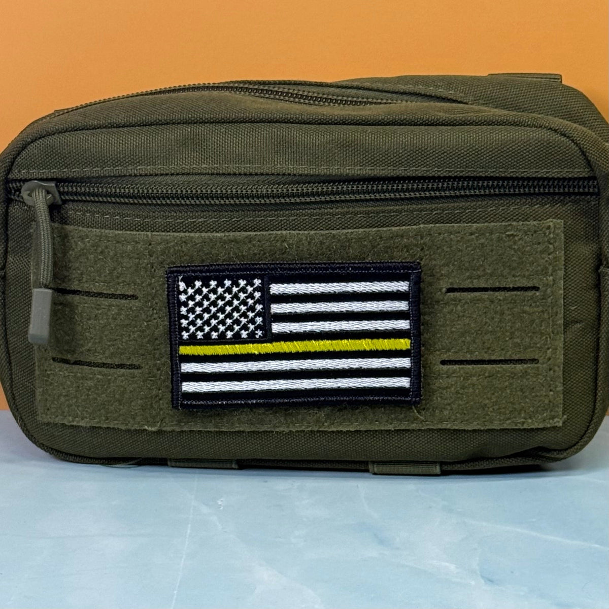 Thin Yellow Line American Flag patch in black and white American flag with one yellow stripe, mounted on an olive utility pouch