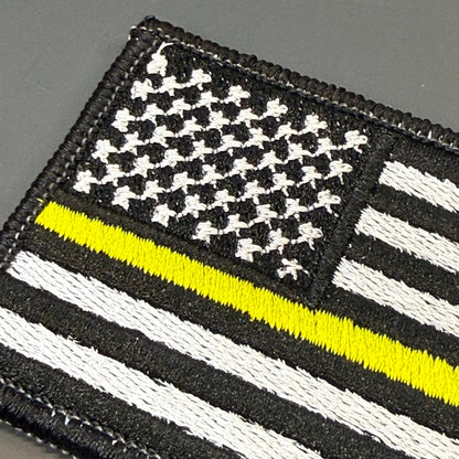 Thin Yellow Line American Flag patch in black and white American flag with one yellow stripe, close-up of embroidery
