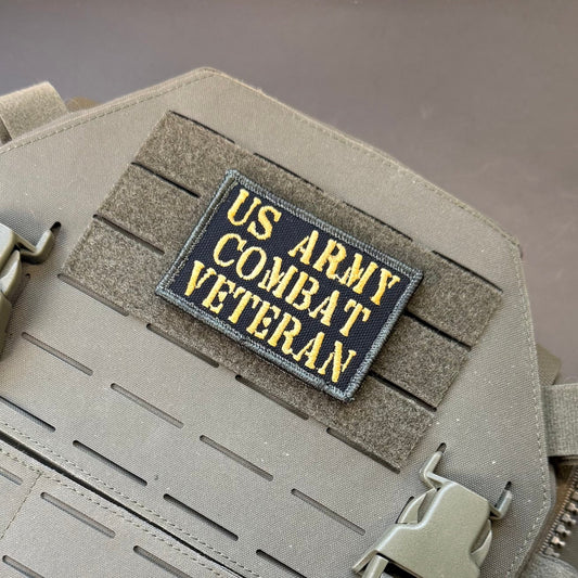 US Army Combat Veteran patch in black with tan lettering, mounted on a tan plate carrier