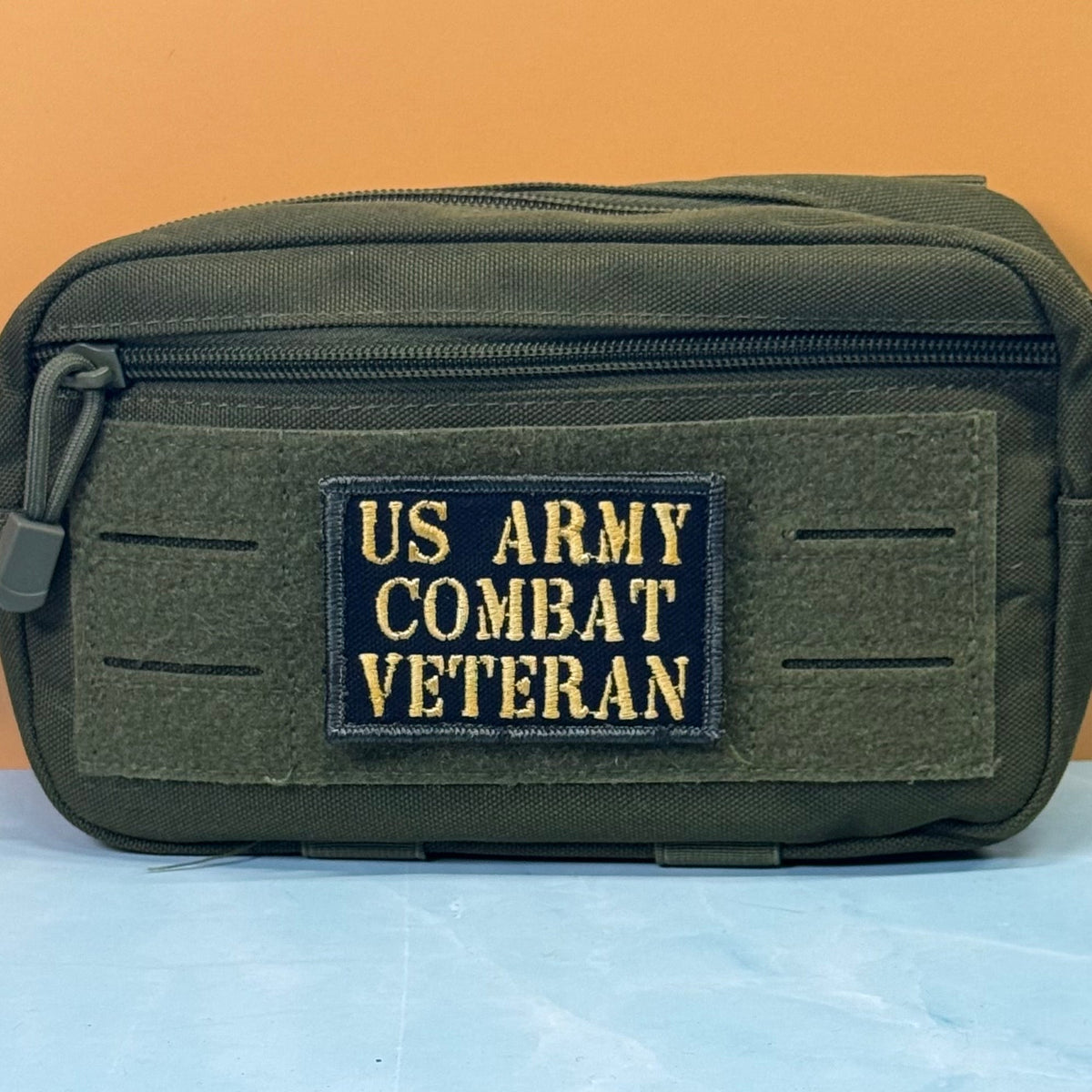 US Army Combat Veteran patch in black with tan lettering, mounted on an olive utility pouch