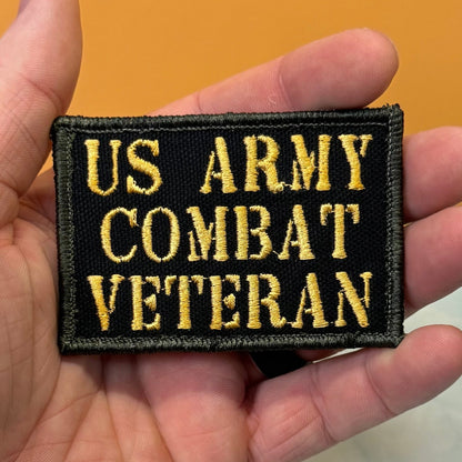 US Army Combat Veteran patch in black with tan lettering, held in a hand
