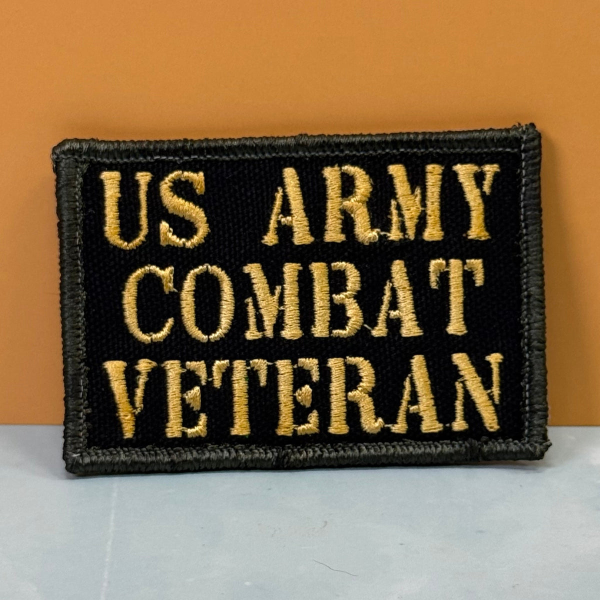 Front view of US Army Combat Veteran patch in black with tan lettering