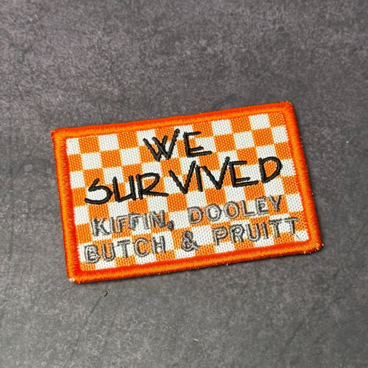 Front view of We Survived, Tennessee Football patch in orange and white checkerboard with black handwritten lettering