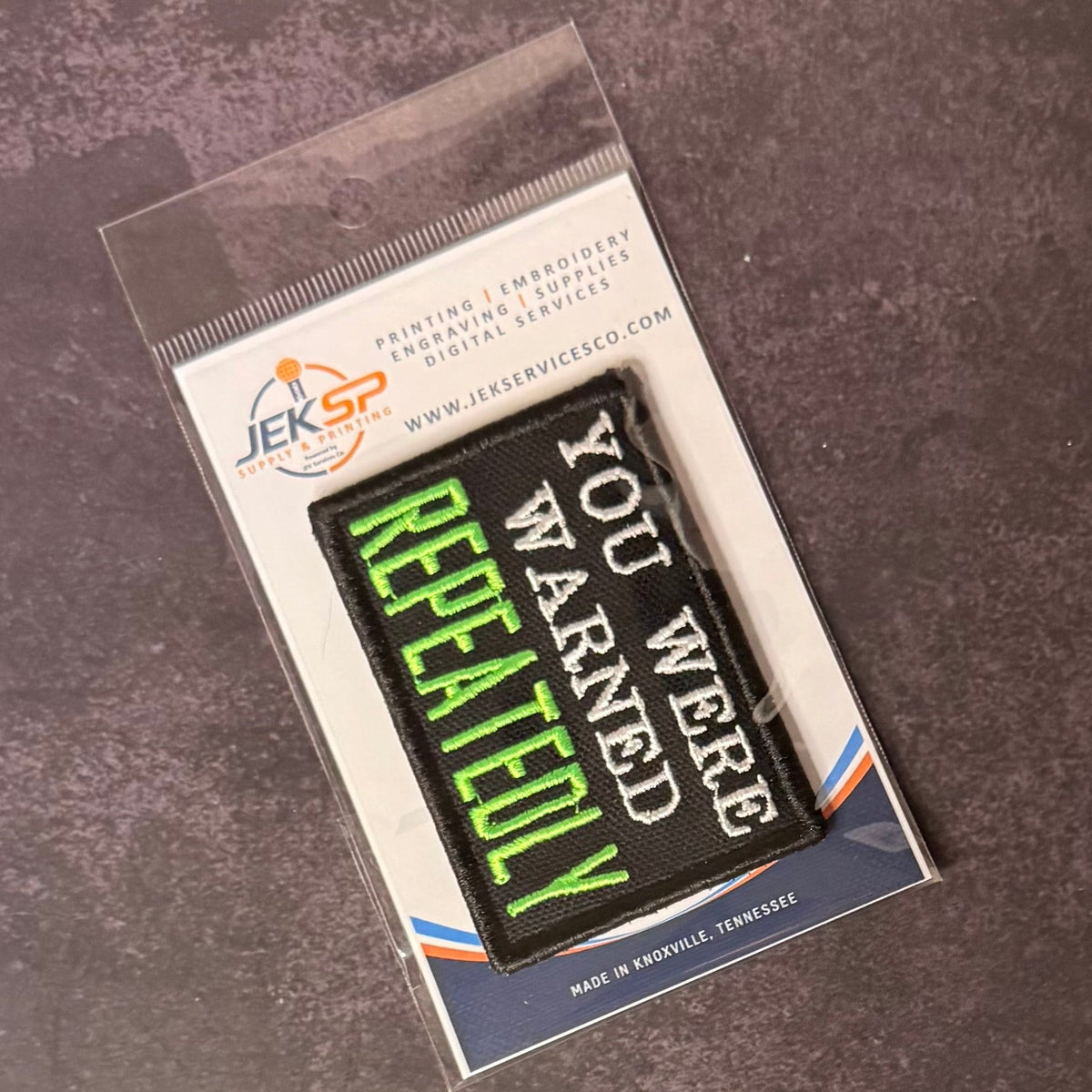 You Were Warned, Repeatedly patch in black with white lettering and bright green REPEATEDLY text, in clear retail packaging